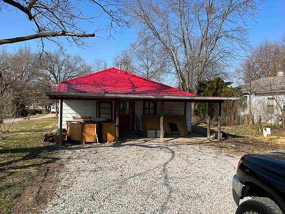 A small house with a red roof and a car parked in front of it.