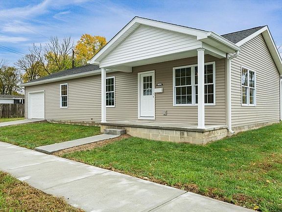 A small house with a porch and a garage is for sale.
