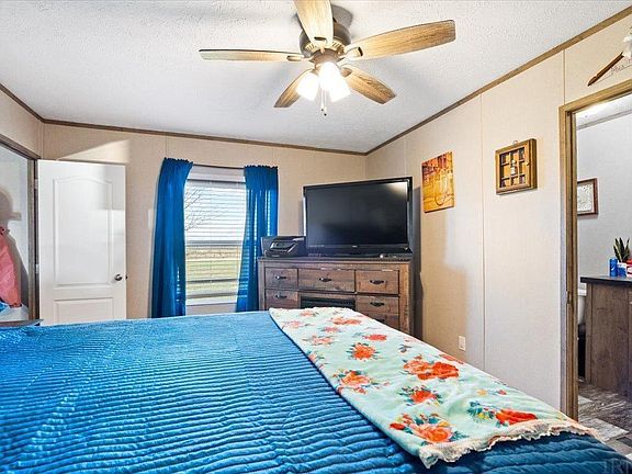 A bedroom with a bed , television , dresser and ceiling fan.