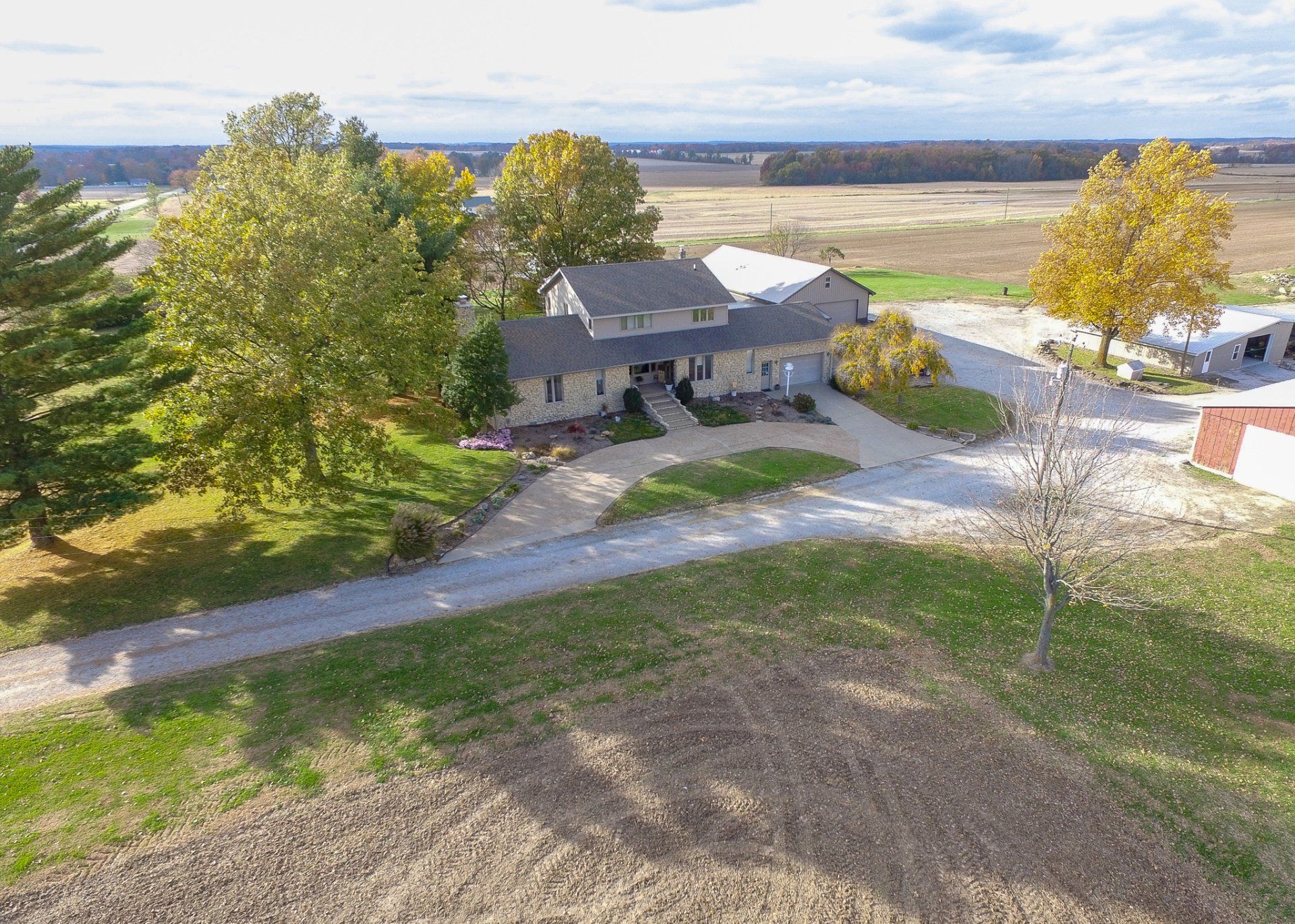 An aerial view of a house in the middle of a field surrounded by trees.