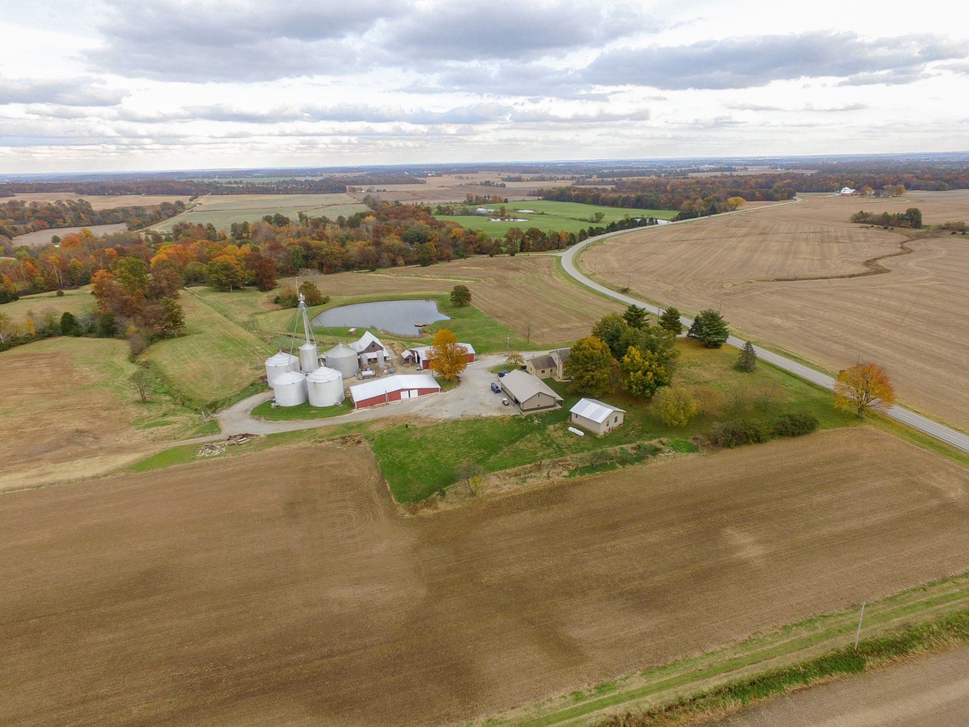 An aerial view of a farm surrounded by fields on a cloudy day.