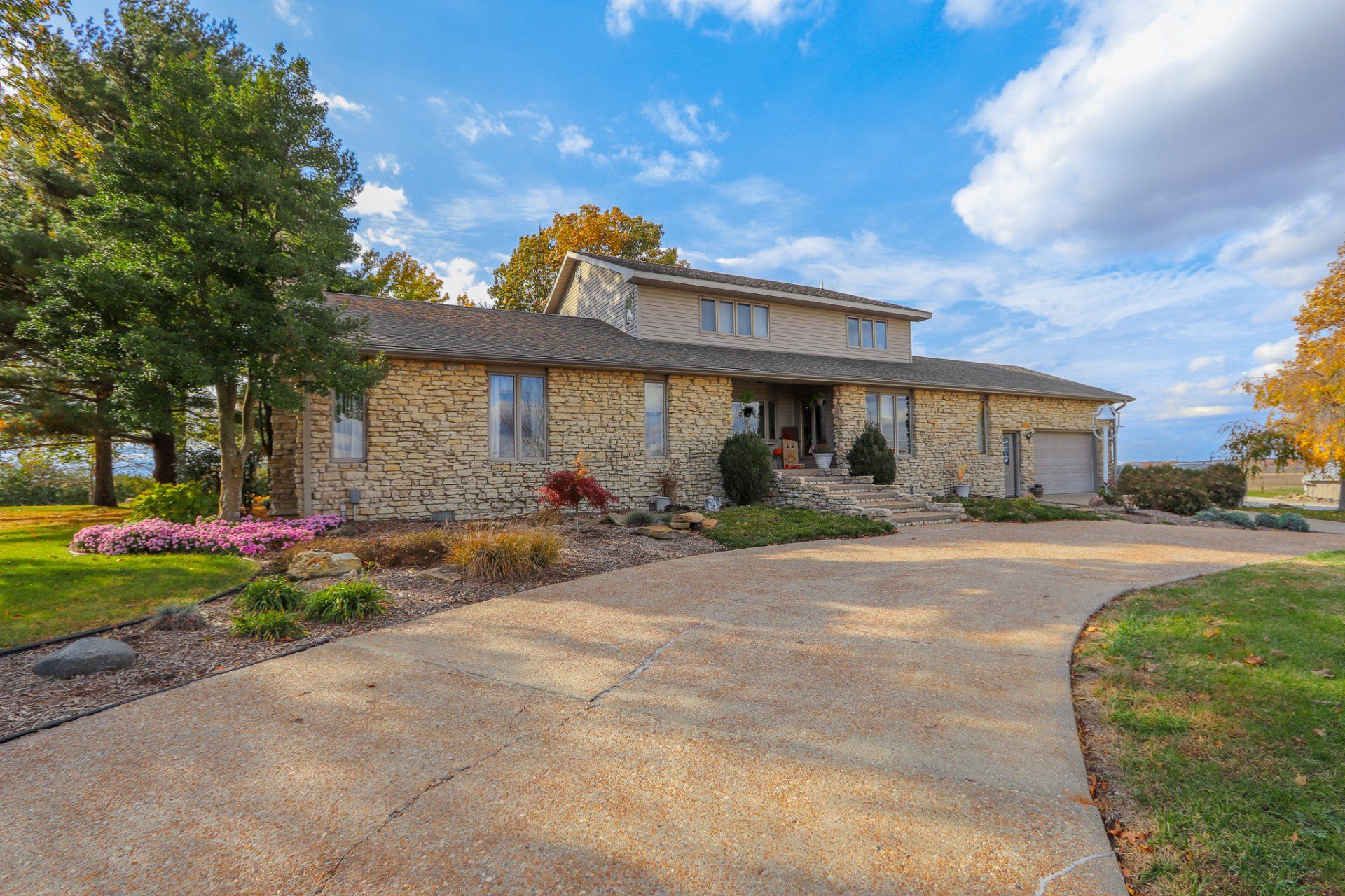 A large stone house with a concrete driveway leading to it.