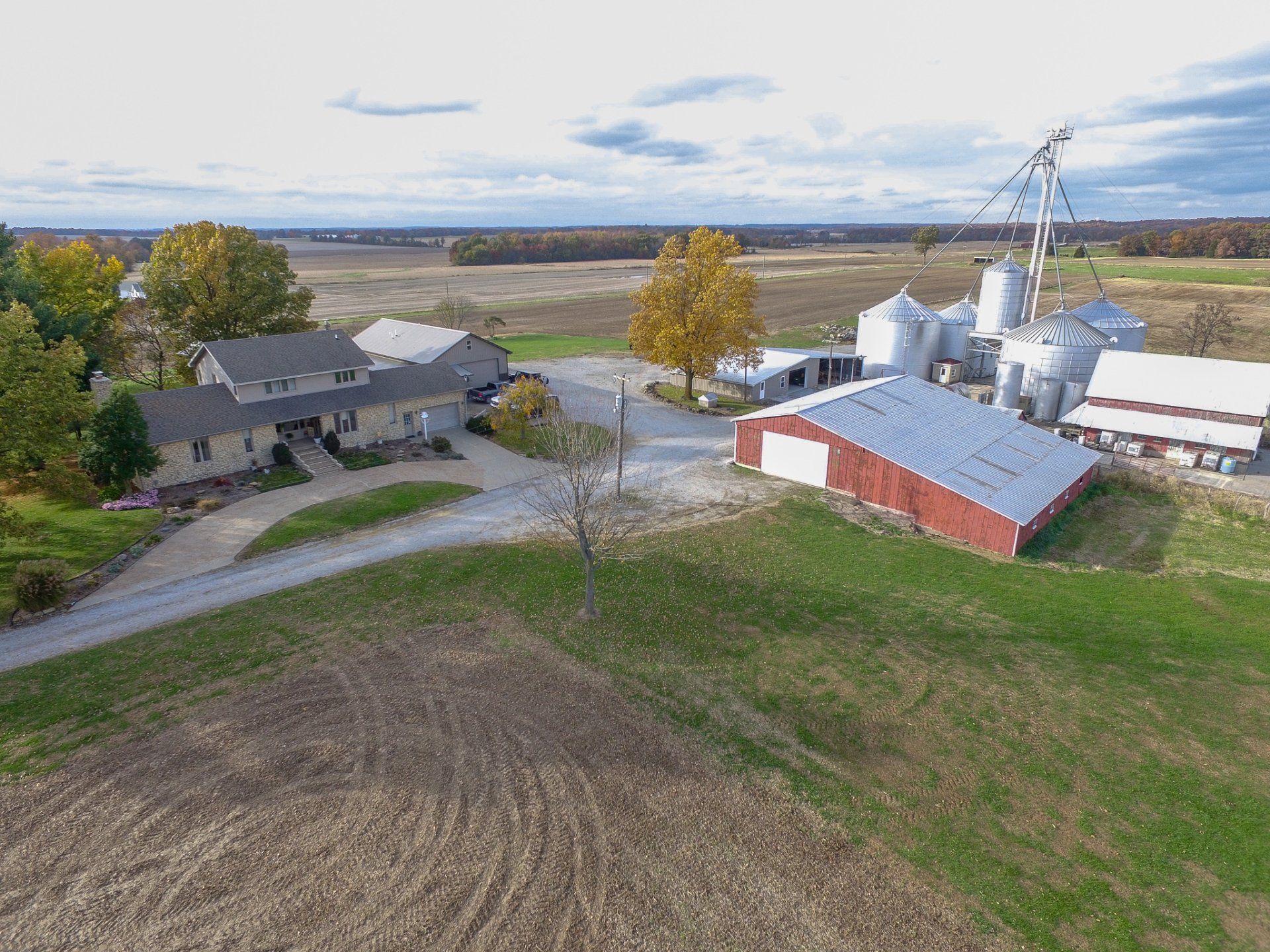 An aerial view of a farm with a red barn and silos.