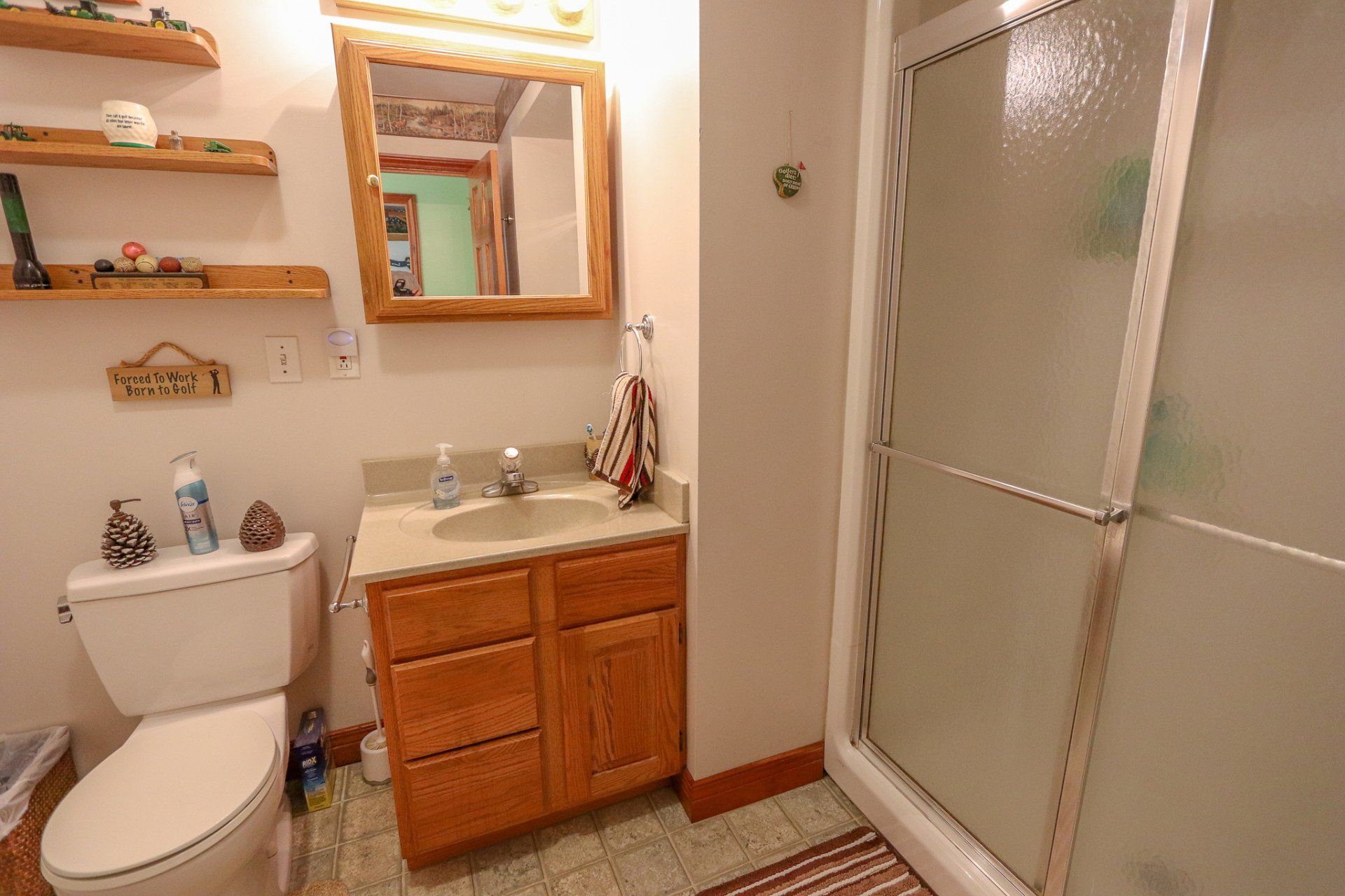 A bathroom with a toilet , sink , mirror and shower.