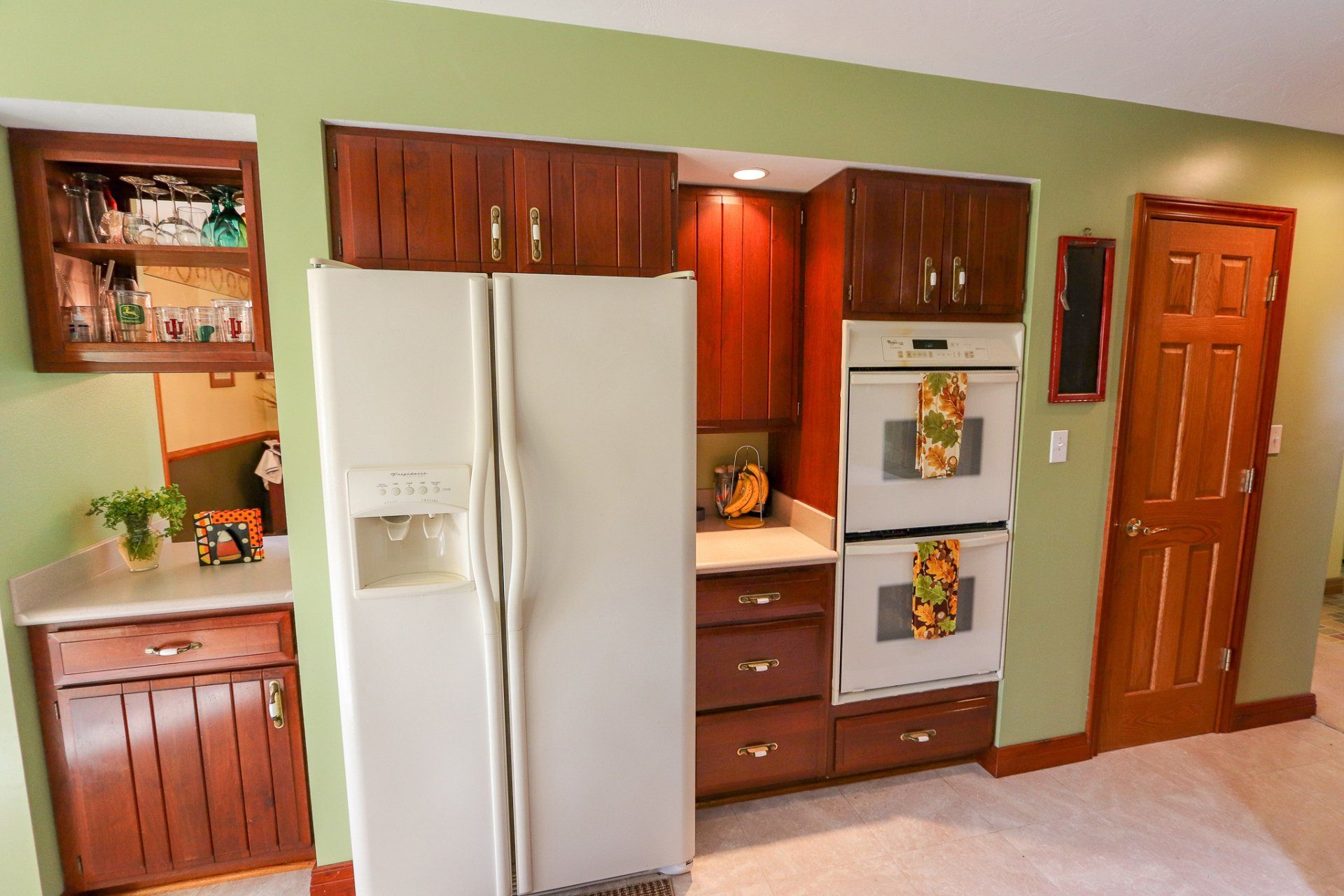 A kitchen with a white refrigerator and two ovens