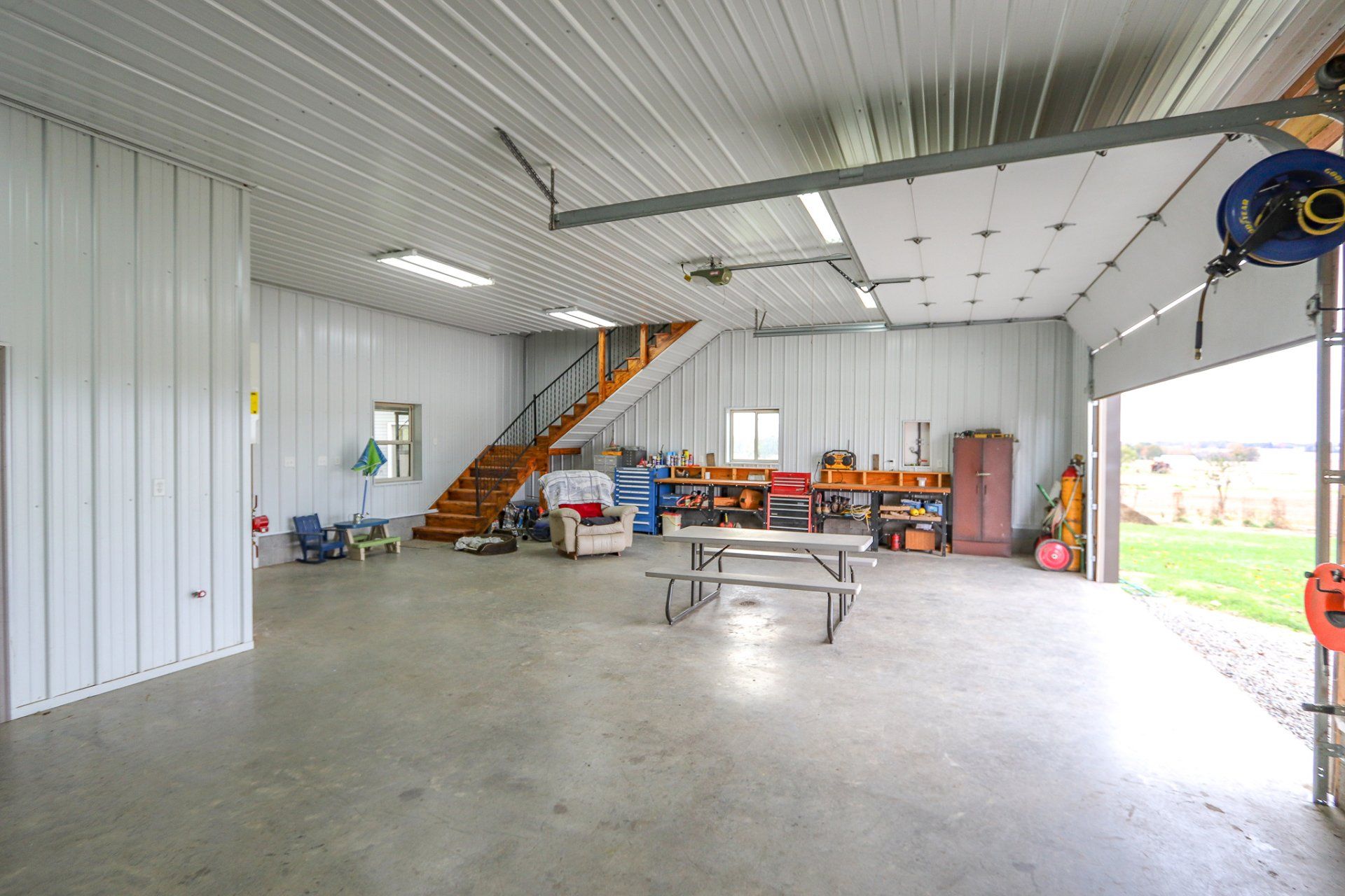 A large garage with a picnic table and stairs leading up to the second floor.