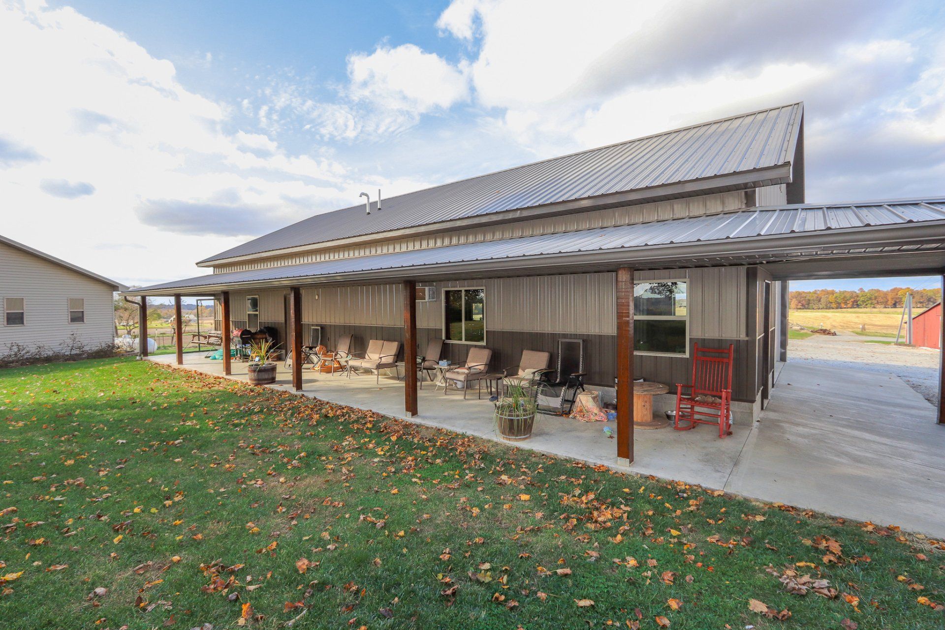 A large house with a covered porch and chairs in front of it.