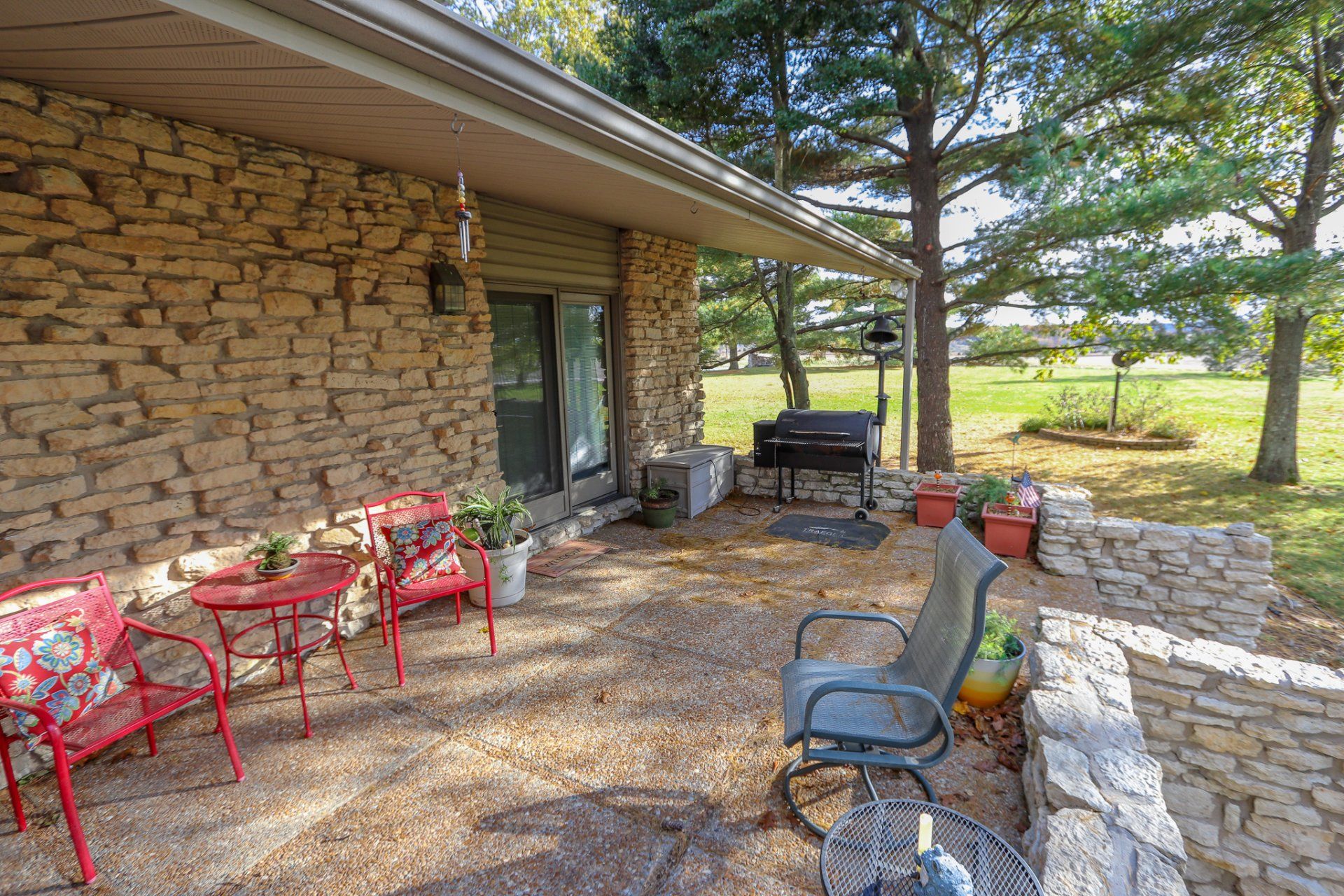 A stone house with a patio area with chairs and a table.
