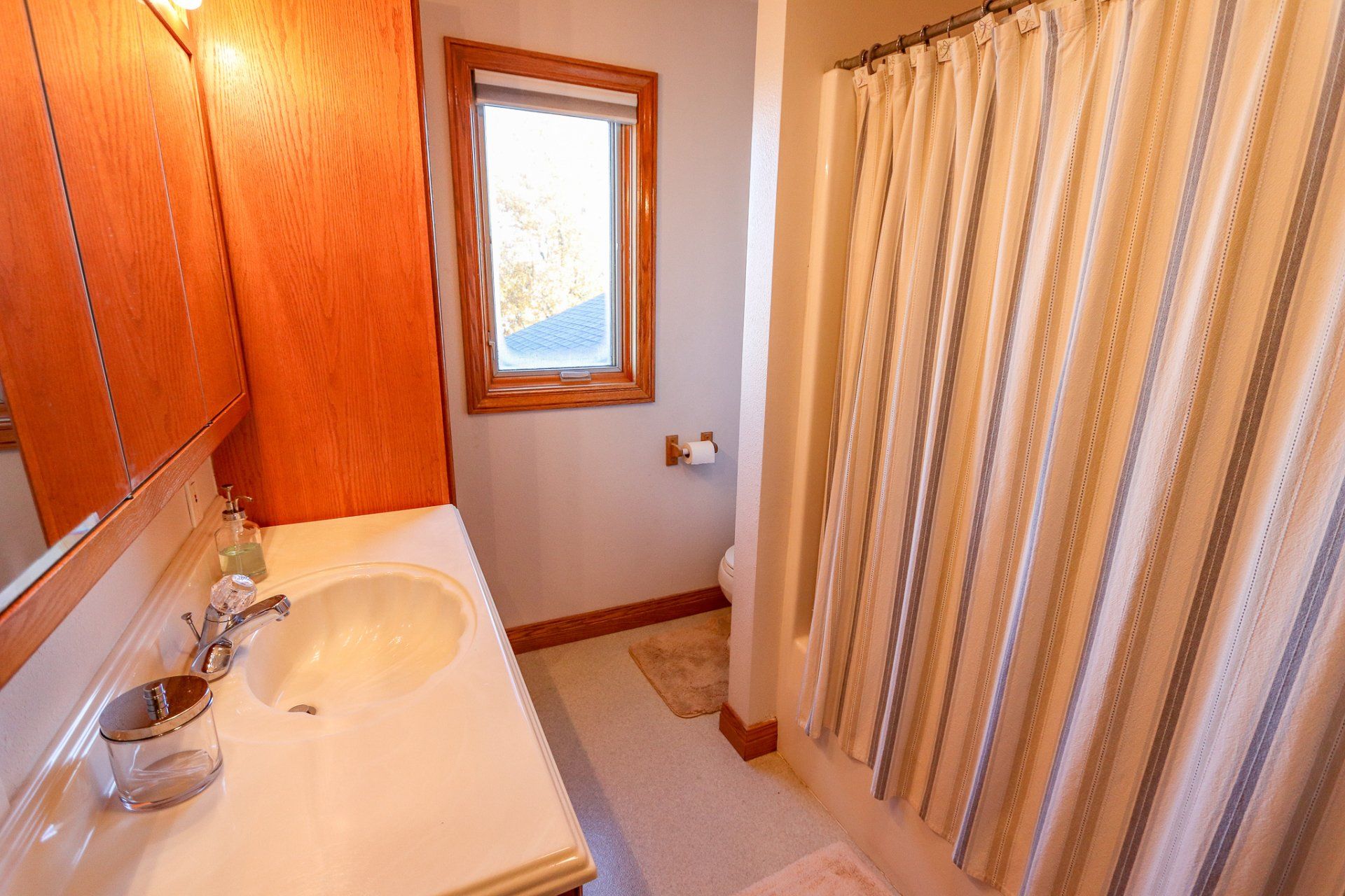 A bathroom with a sink , mirror and shower curtain.