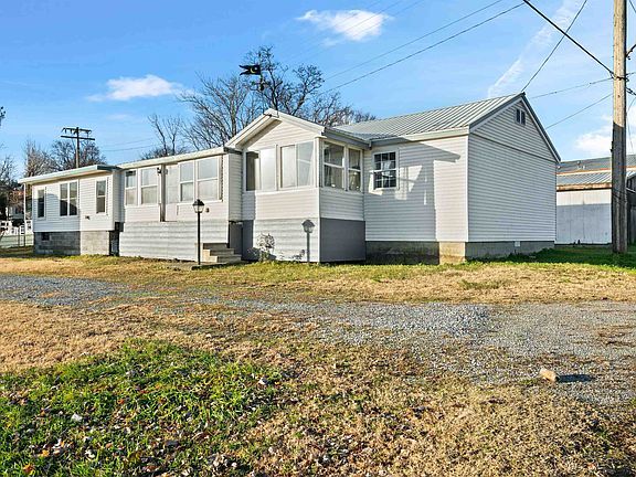 A mobile home is sitting in the middle of a grassy field.