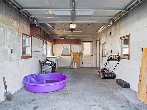 A garage with a purple pool and a lawn mower.