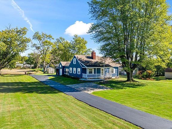 An aerial view of a blue and white house with a driveway leading to it.