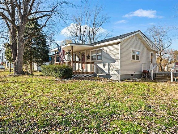 A small white house is sitting on top of a lush green field.