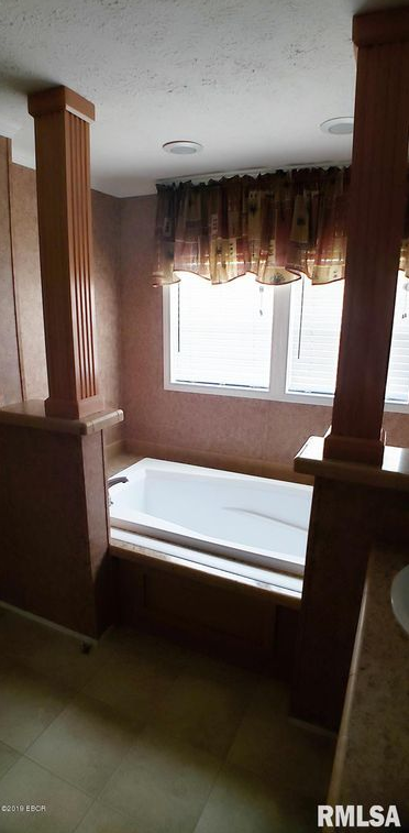 A bathroom with a tub and a window.