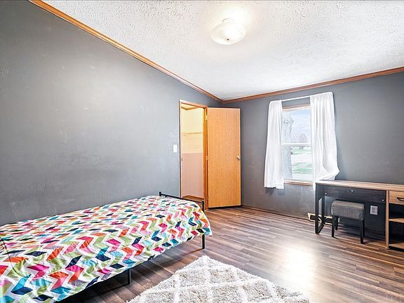 A bedroom with a bed , desk , and window.