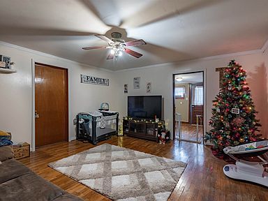 A living room with a christmas tree and a ceiling fan.