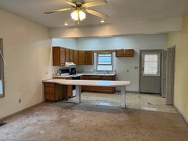 There is a ceiling fan in the kitchen and a table in the living room.