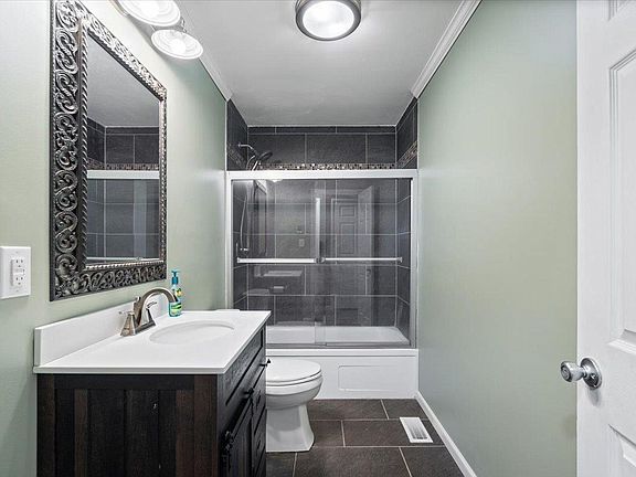 A bathroom with a toilet , sink , mirror and bathtub.