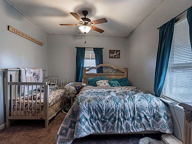 A bedroom with two beds , a crib and a ceiling fan.
