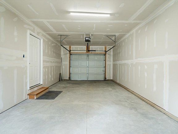 An empty garage with a garage door open and a light on the ceiling.