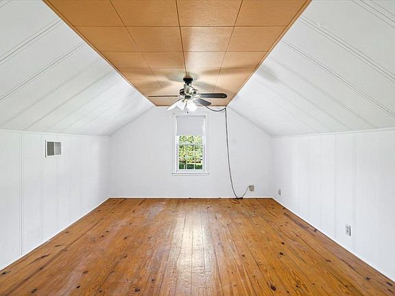 An empty room with wooden floors and a ceiling fan.