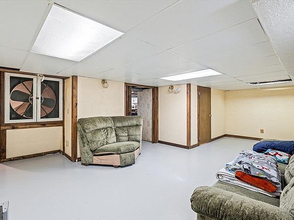 A living room with a couch , chair , and fan.