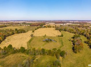 An aerial view of a large lush green field surrounded by trees.
