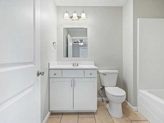 A bathroom with a toilet , sink , mirror and bathtub.