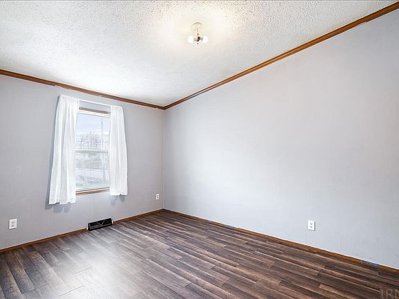 An empty bedroom with hardwood floors and a window.