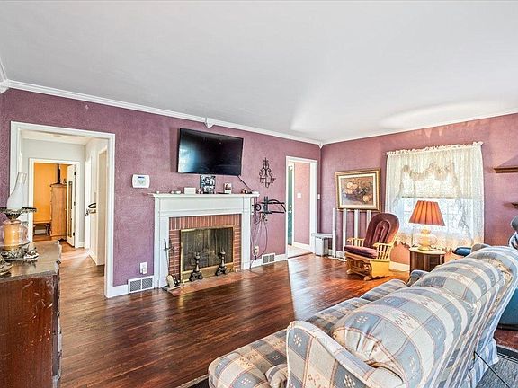 A living room with a couch , chair , fireplace and television.