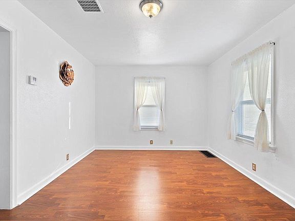An empty living room with hardwood floors and white walls.