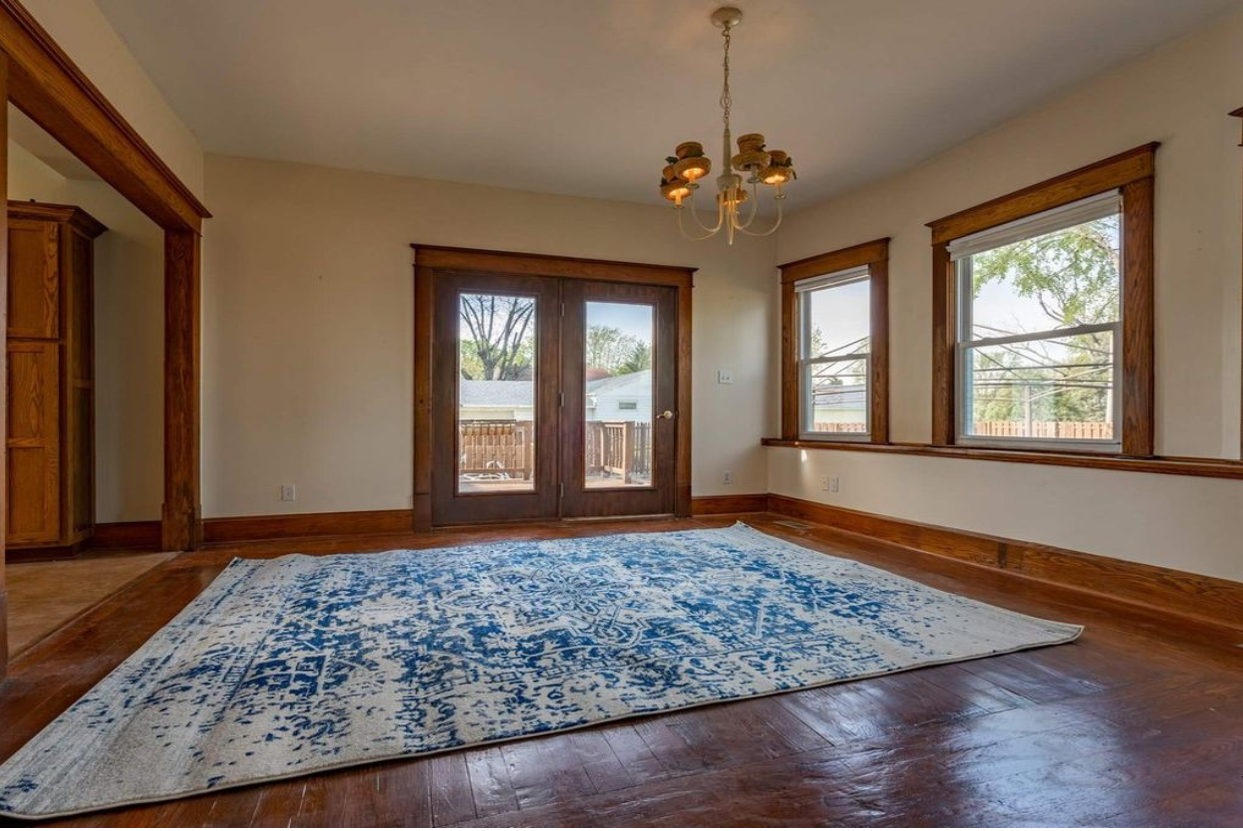 An empty room with a rug on the floor and a chandelier hanging from the ceiling.