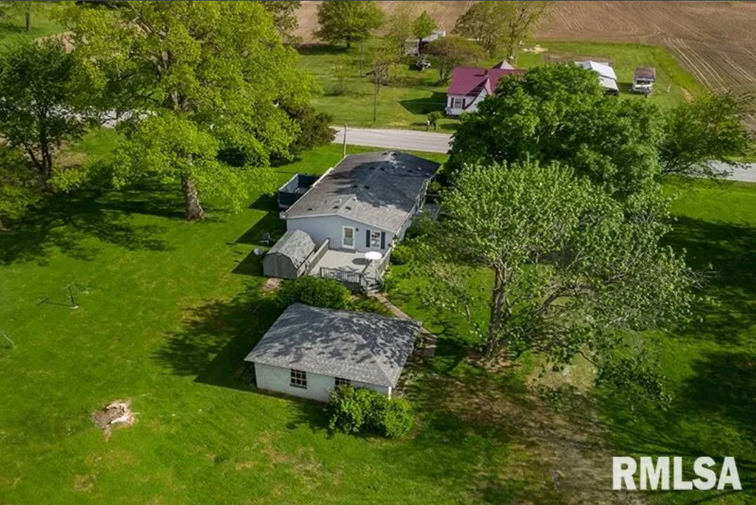 An aerial view of a house in the middle of a lush green field.