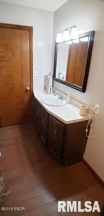A bathroom with a sink , mirror and cabinets.