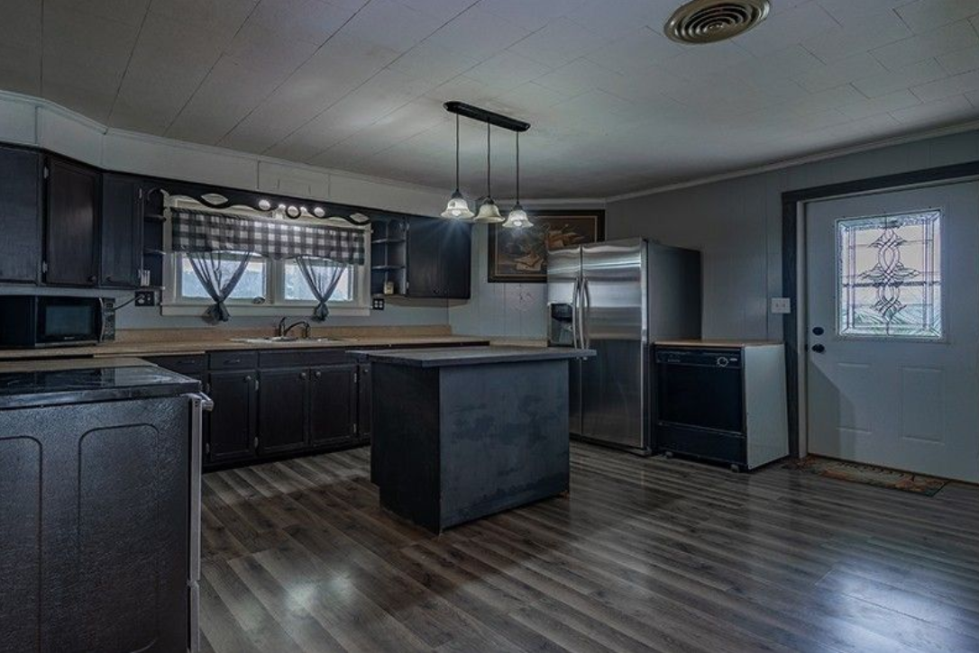 A kitchen with stainless steel appliances and a large island in the middle of the room.