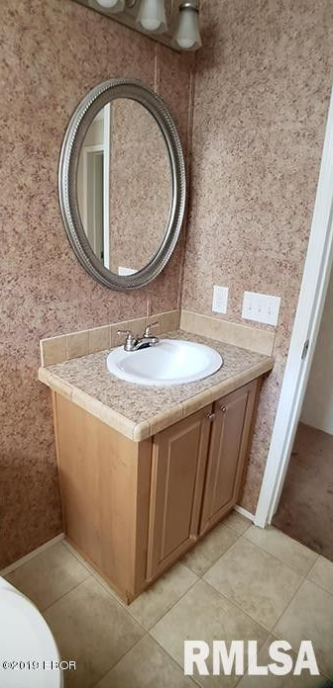 A bathroom with a sink , mirror and toilet.