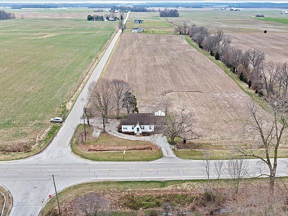 An aerial view of a house in the middle of a field next to a road.