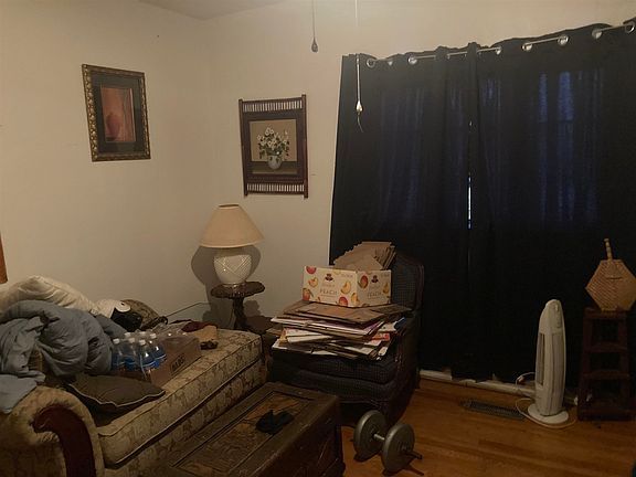 A living room with a couch , chair , table , lamp and black curtains.