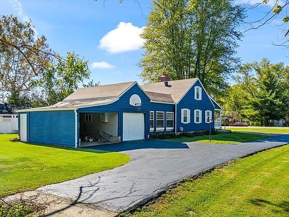 A blue house with a garage and a driveway in front of it.