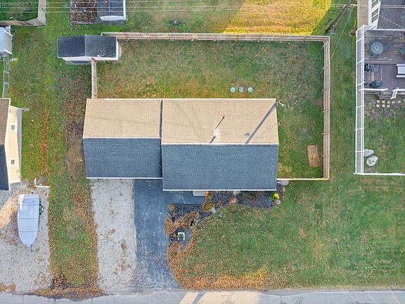 An aerial view of a house with a black roof and a lot of grass.