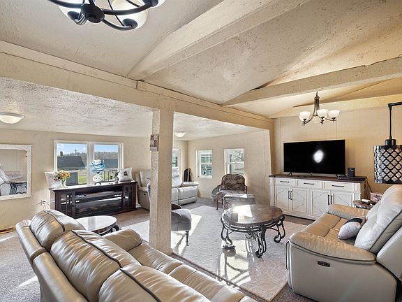 A living room with a couch , chairs , table and television.