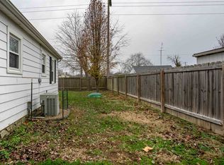 A backyard with a wooden fence and a white house.