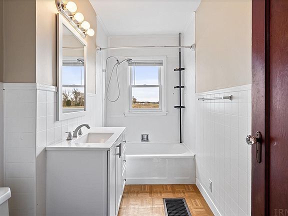 A bathroom with a sink , tub , mirror and window.