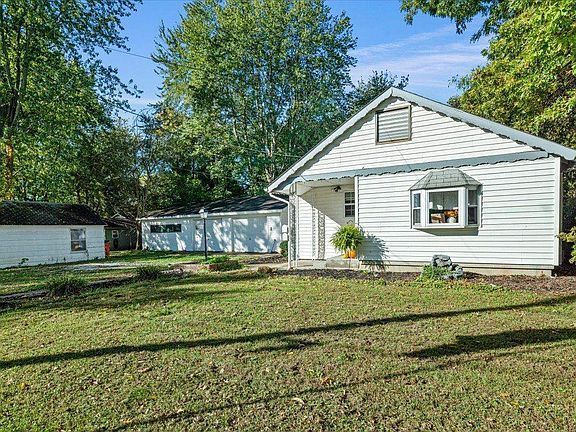A small white house with a large lawn in front of it.