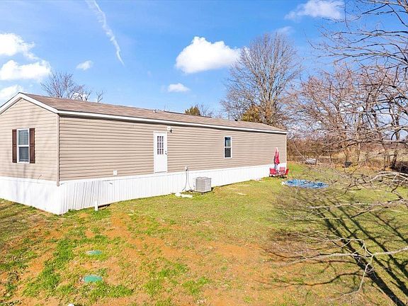 A mobile home is sitting in the middle of a grassy field.