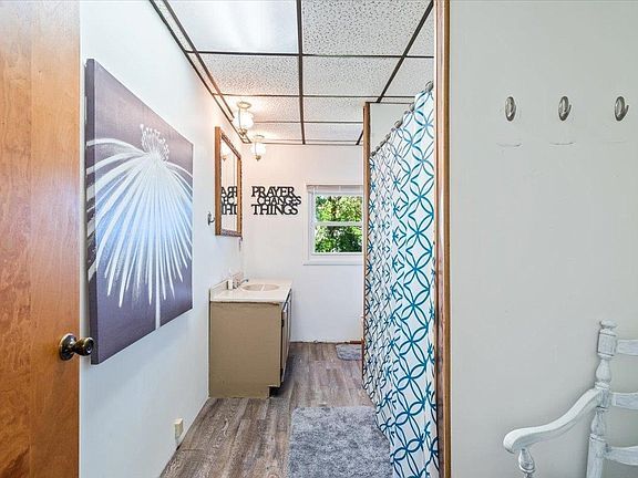A bathroom with a sink , mirror and shower curtain.