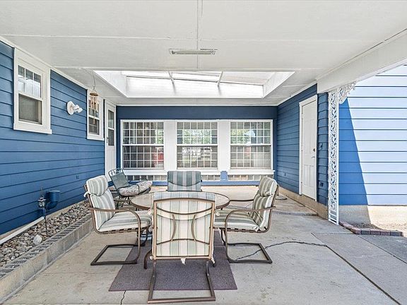 A patio with a table and chairs in front of a blue house.