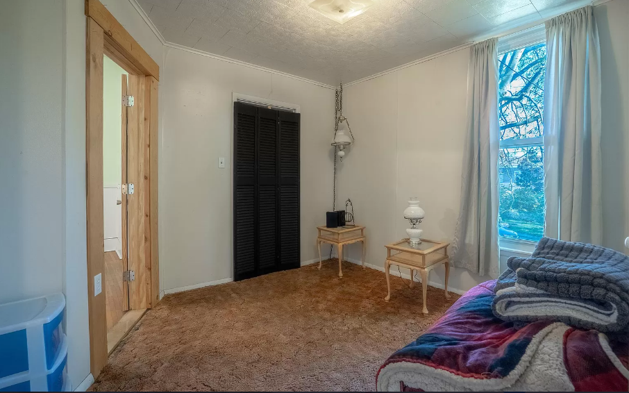 A bedroom with a bed , nightstands , and a window.