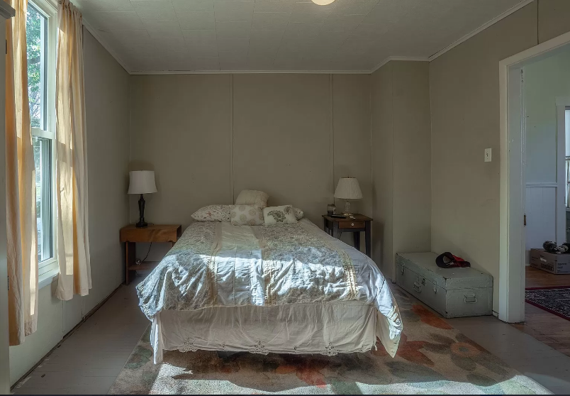 A bedroom with a bed , two lamps , and a window.