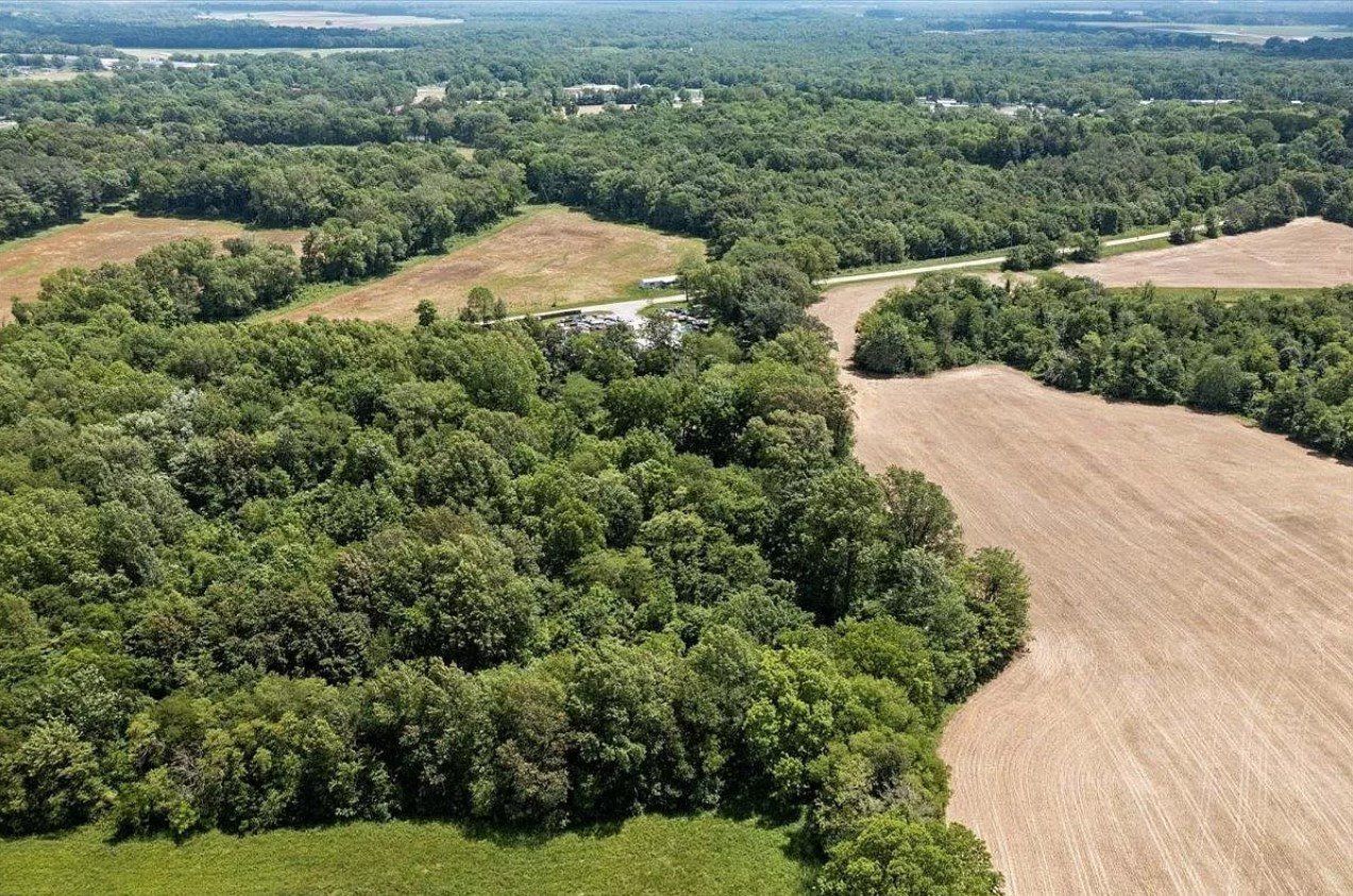 An aerial view of a lush green forest surrounded by fields.